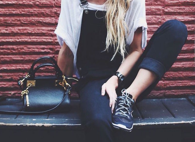 blonde woman in front of red wall with black overalls