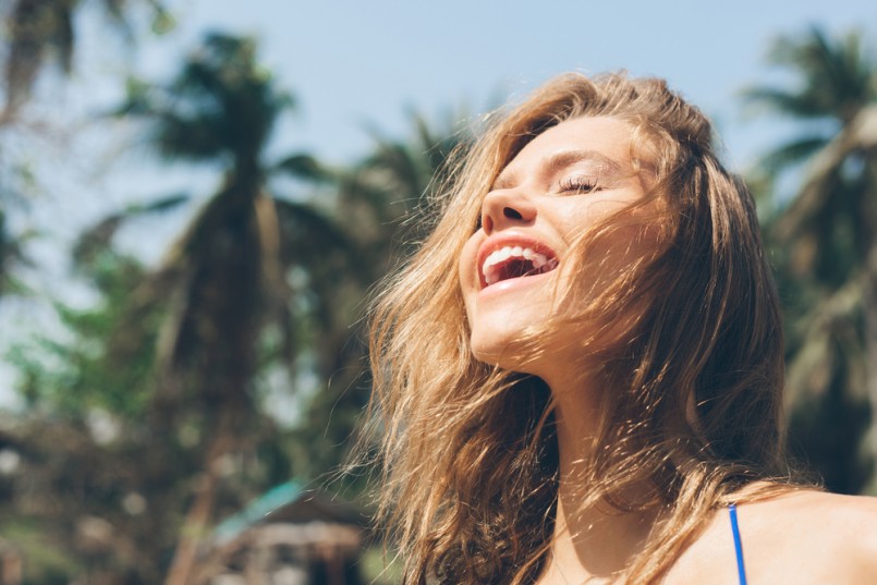Beauty Sunshine Girl Portrait. Pretty happy woman enjoying summer outdoors. Sunny Summer Day under the Hot Sun on the Beach