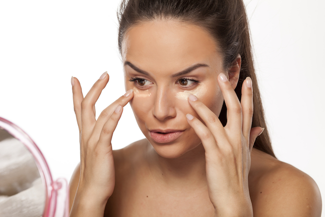 young woman apply different shades of liquid foundation on her face