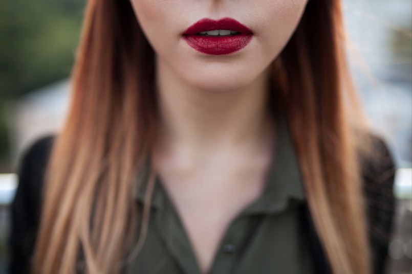 close up shot of sexy red female lips; macro shot of purple lipstick on lips of young attractive woman