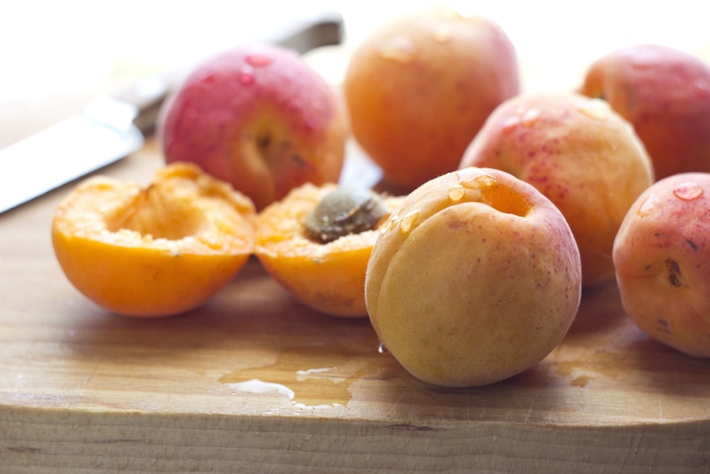 Freshly washed apricots on wooden cutting board with knife. Macro with shallow dof