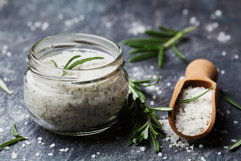 Sea salt scented herb rosemary on black stone background, vintage style