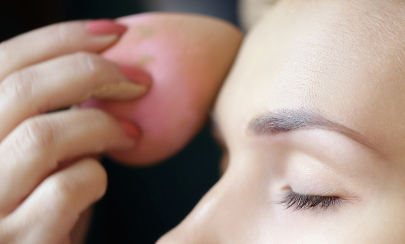 Applying foundation by sponge on face for make-up