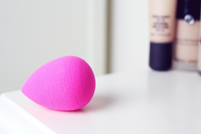 pink beautyblender on white counter with foundation