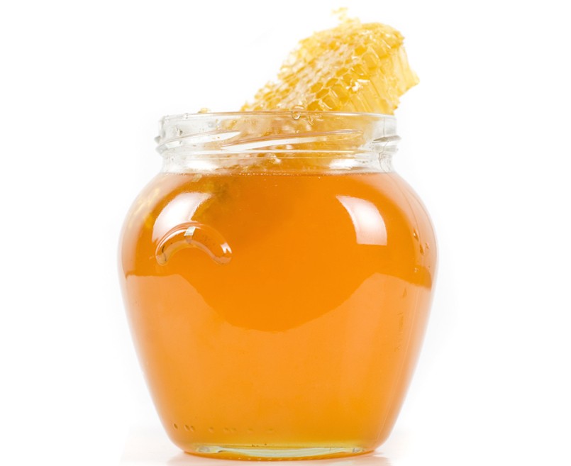 jar of organic honey on white background