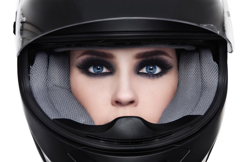 Close-up portrait of young beautiful woman in biker helmet over white background
