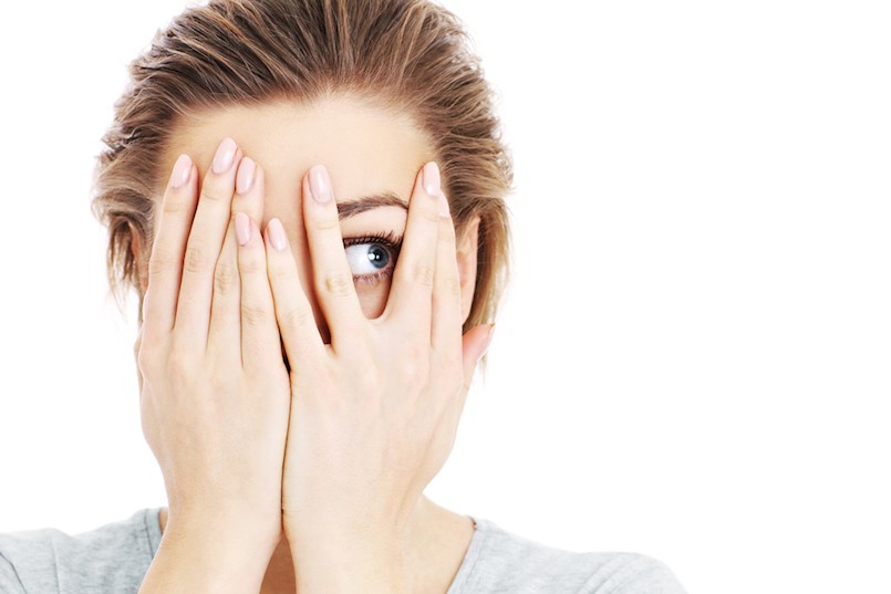 A picture of a scared woman covering her eyes over white background