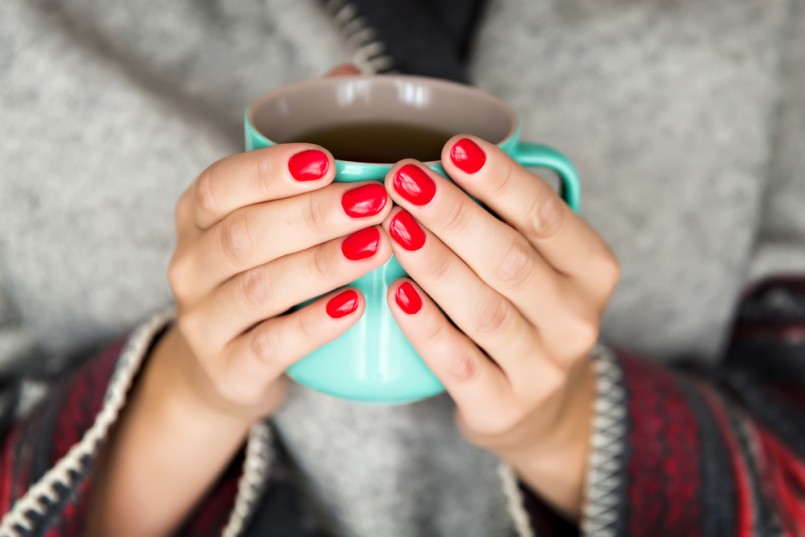 female hands holding a mug of hot tea