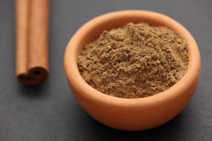 Cinnamon powder and cinnamon stick on black background