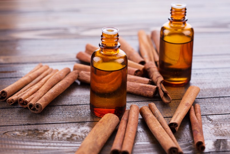 Essential aroma oil with cinnamon on wooden background