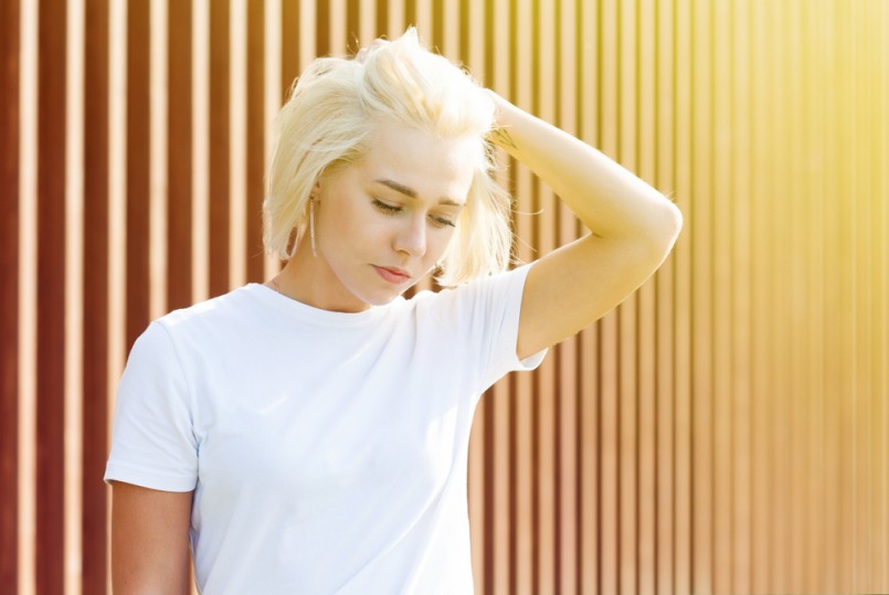 Girl with platinum blond hair in white t-shirt on woden background with flare
