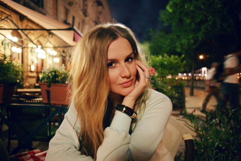 Young pretty blonde woman sitting at cafe in evening time