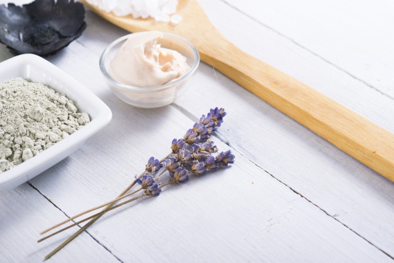 spa massage clay powder, soaps, bath salt, shea butter and lavenders on white wood table background