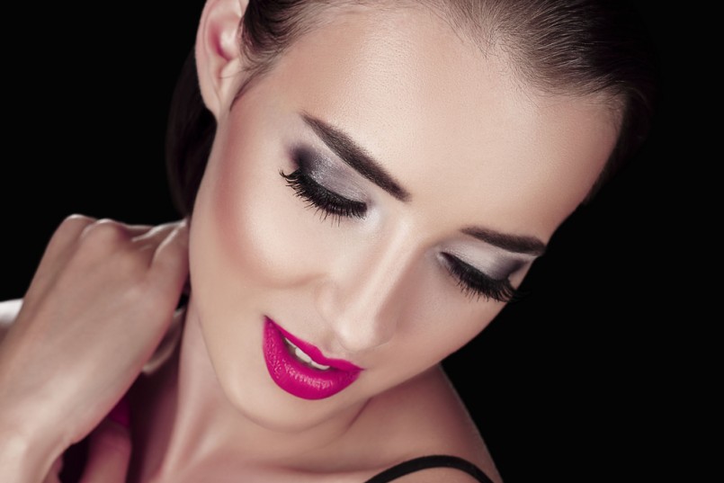 Beauty Woman with Perfect Makeup. Beautiful Professional Holiday Make-up. Red Pink Lips and Nails. Beauty Girl's Face isolated on Black background