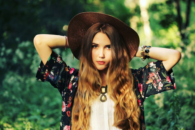 Fashion portrait of beautiful hippie young woman wearing boho chic clothes and summer hat outdoors. Soft warm vintage color tone. Artsy bohemian style