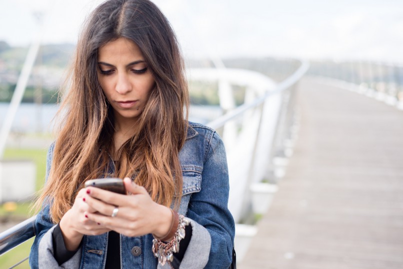 Young brunette woman looking her smart phone outdoors