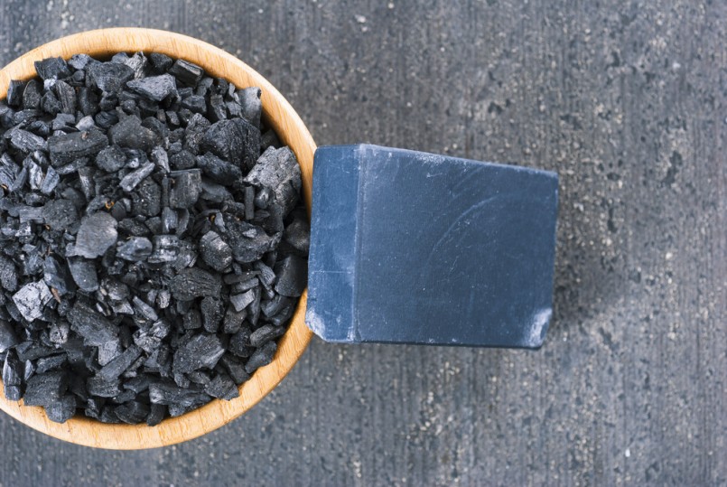 block of natural carbon soap and a pile of coal on black wood table background