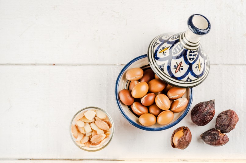 Argan Fruit on a wooden tabletop, Some fruit are without shell, other are in a Moroccan Tajine