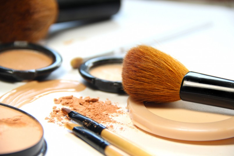 Broken powder, foundation and brushes on the white background