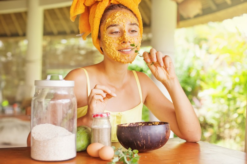 woman smelling a mint leave while doing face mask at home