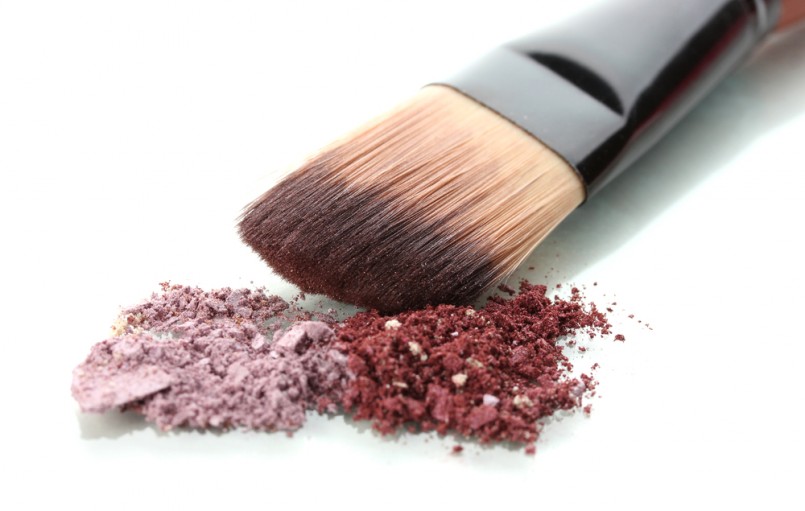 Crushed eyeshadows and brush isolated on white