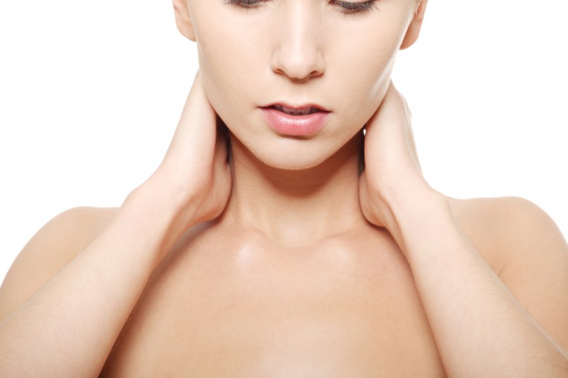 Naked woman touching her neck, head and shoulders close up. Over white background