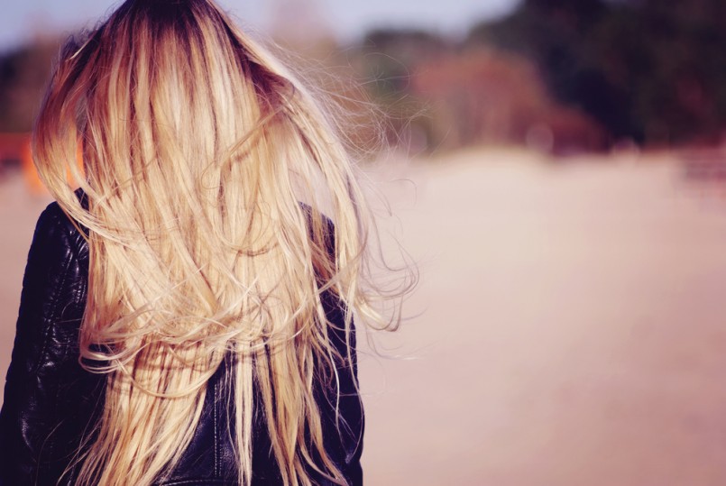 Back view of the young female with beautiful blond straight long hairs in motion