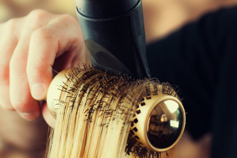 Drying blond hair with hair dryer and round brush