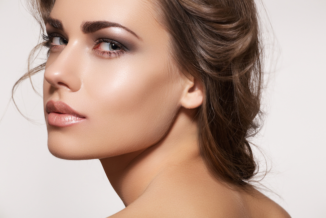 Glamour portrait of beautiful woman model with fresh daily makeup and romantic wavy hairstyle. Fashion shiny highlighter on skin, sexy gloss lips make-up and dark eyebrows