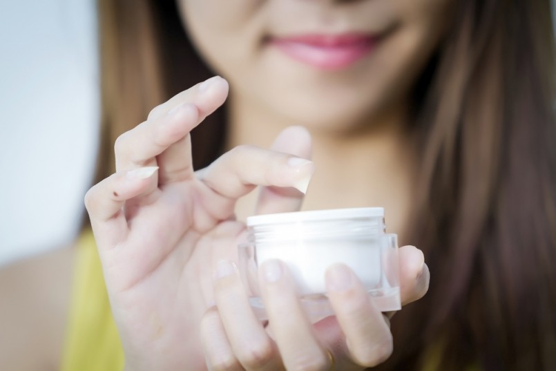 A beautiful woman asia using a skin care product, moisturizer or lotion and Skincare taking care of her dry complexion. Moisturizing cream in female hands