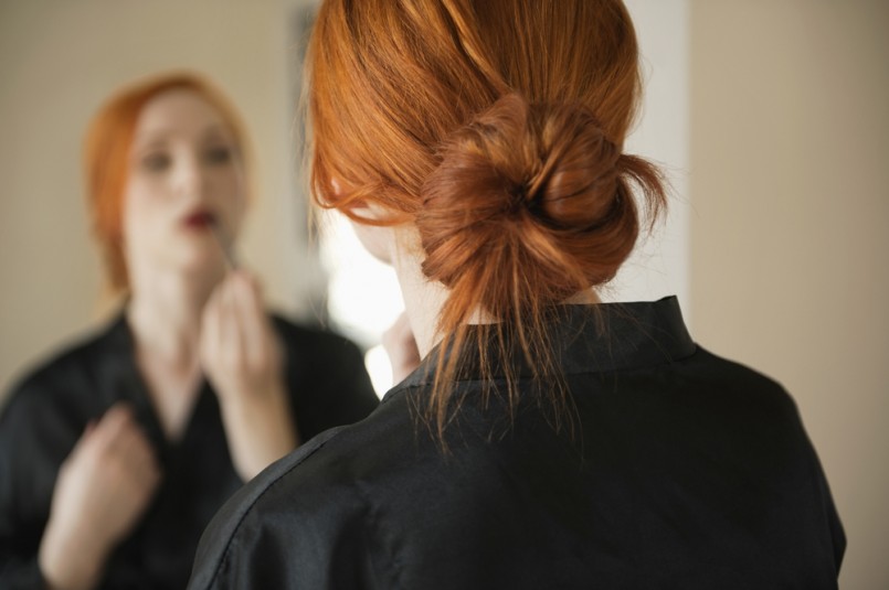 Back view of young woman applying makeup