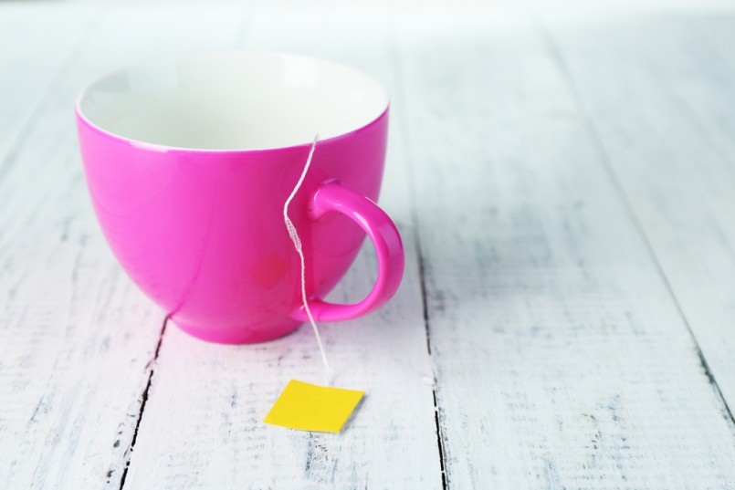 Cup with tea bag on wooden table close-up