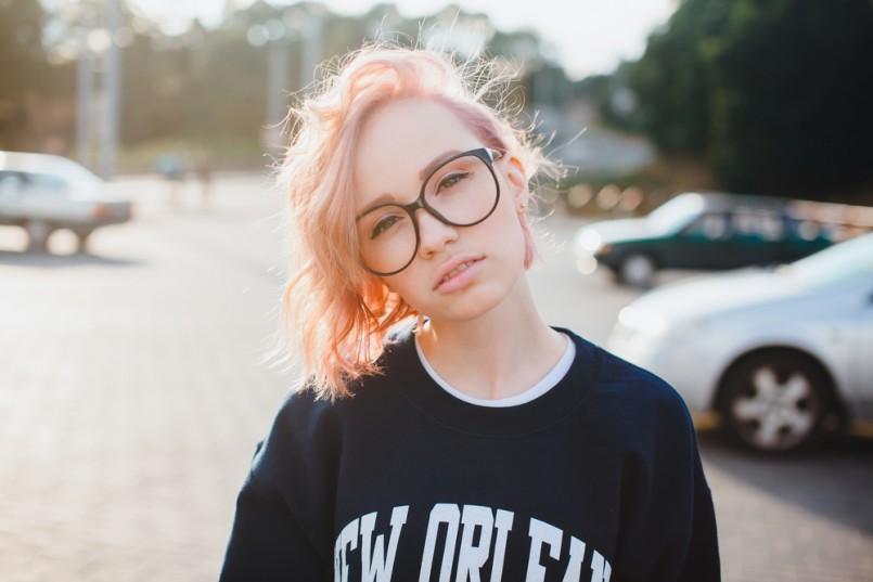 Fashion details.Close up trendy image os sexy fit hipster woman wearing retro denim jeans and warm sweater,swag style,print t-shirt. posing at he street at sunny day.pink hair