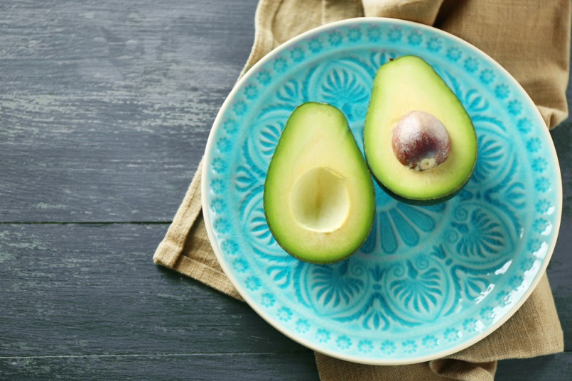 Sliced avocado on plate, on wooden background