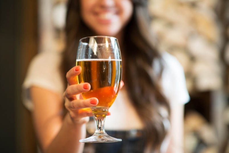 leisure, drinks, degustation, people and holidays concept - close up of smiling woman hand holding glass of draft lager beer