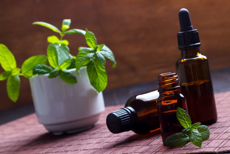 Mint essential oil in small bottles, aromatherapy setting on wooden background.Selective focus