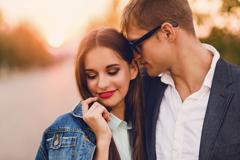Close up lifestyle toned image of young couple in love hugging. . Pretty young girl in jeans jacket and her handsome boyfriend dating. Romantic mood.