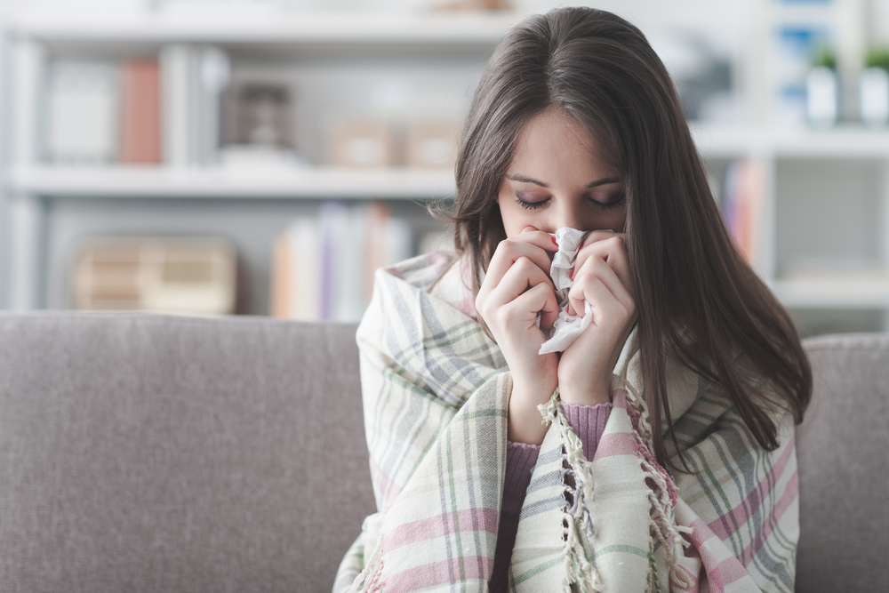 sick-young-woman-at-home-on-the-sofa-with-a-cold-she-is-covering-with-a-blanket-and-blowing-her-nose