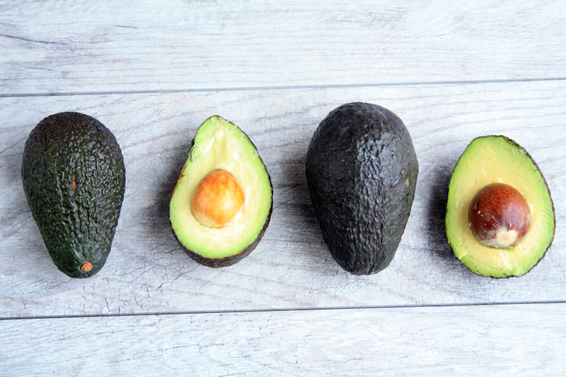 two avocados half and two whole avocados on a gray wooden background/ Half and Whole avocado/avocados