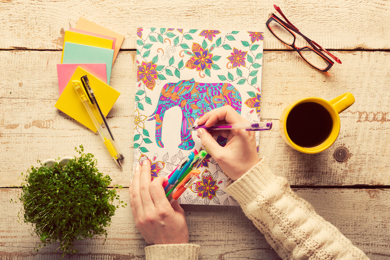 Woman coloring an adult coloring book, new stress relieving trend, mindfulness concept, hand detail